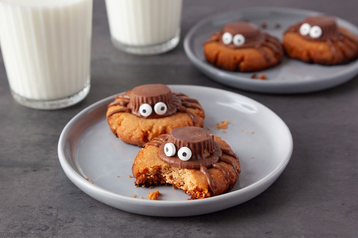 Close up of a few Taste of Home Spider Cookies, glasses of milk in background