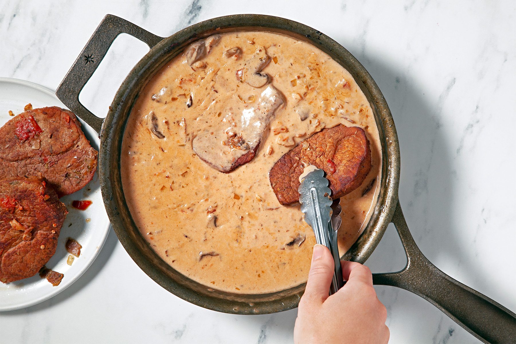 Return meat to skillet and turn to coat with sauce; overhead shot;