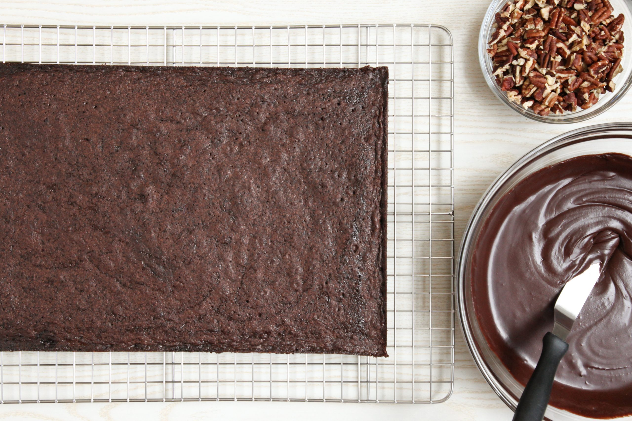 Topping brownies with chocolate frosting and toasted pecans