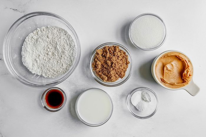 Ingredients for Taste of Home vegan peanut butter cookies in glass bowls on a marble surface.