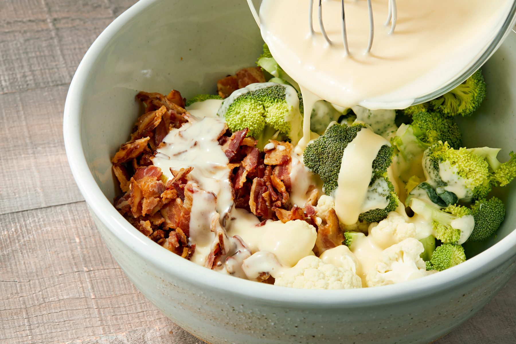 3/4th shot of Pouring dressing over salad