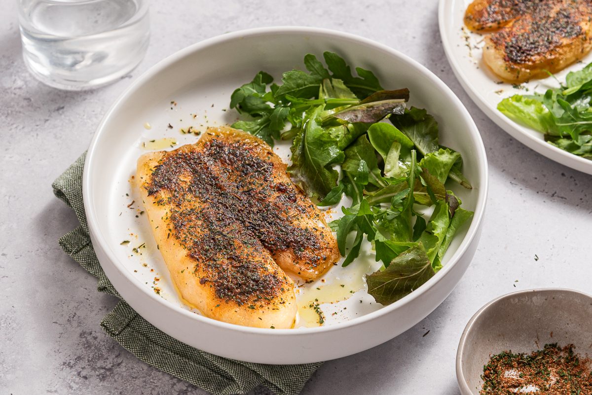 Plates With Baked Tilapia And Green Salad Leaves