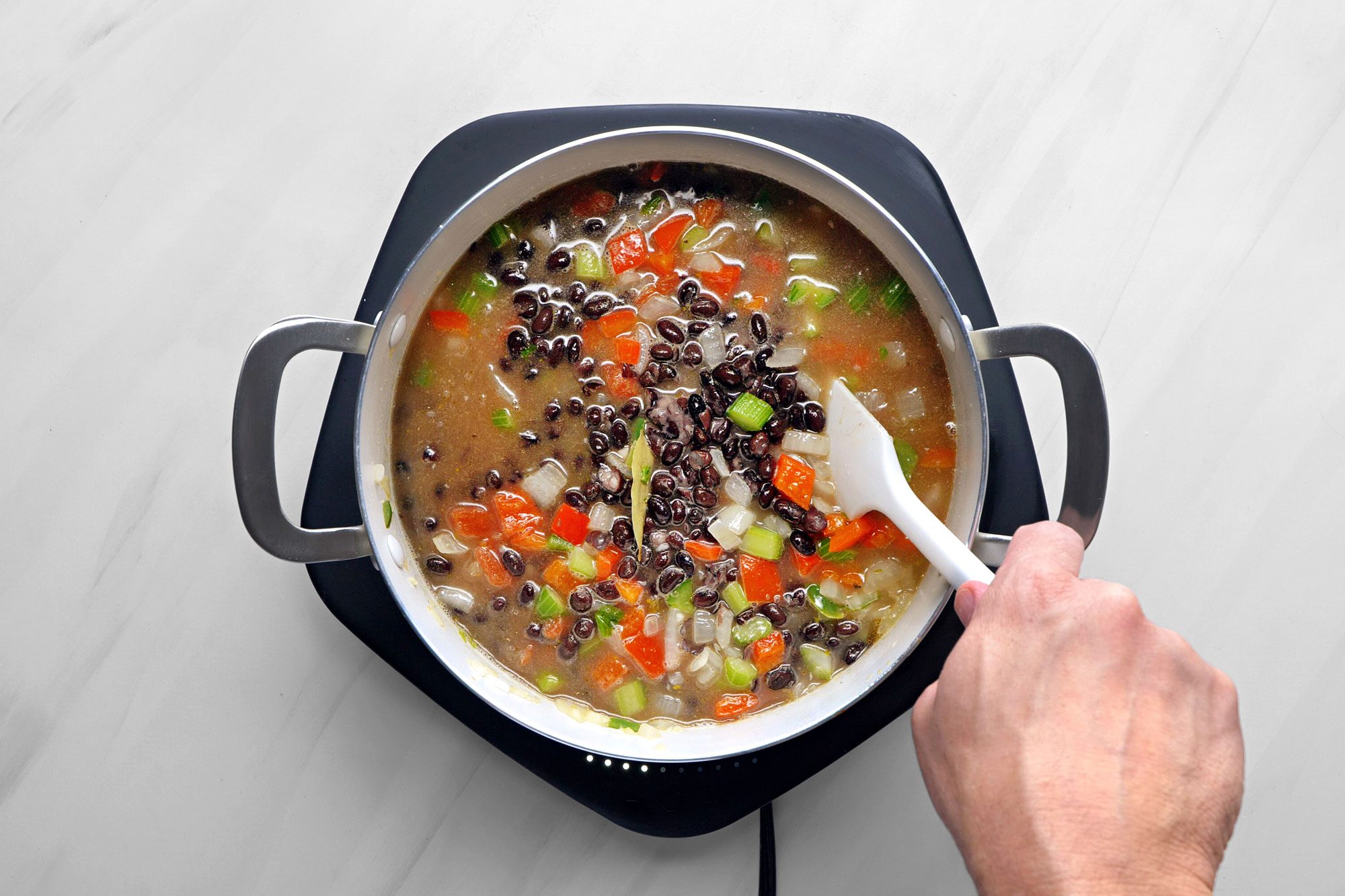Stir in the broth, tomatoes, cumin, coriander, hot sauce, pepper, bay leaf, mashed black beans and remaining whole beans.