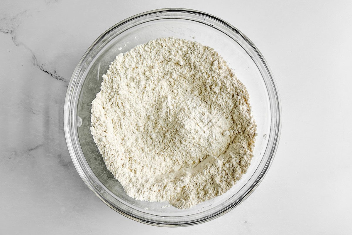 Dry ingredients for Taste of Home Blueberry Biscuits in a glass bowl on a marble surface