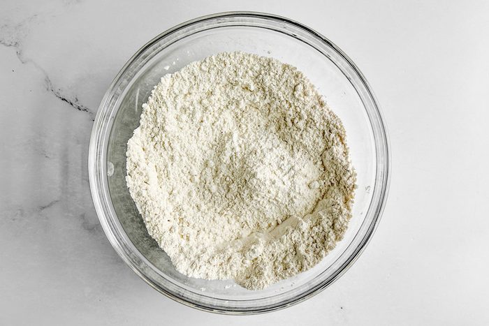 Dry ingredients for Taste of Home Blueberry Biscuits in a glass bowl on a marble surface