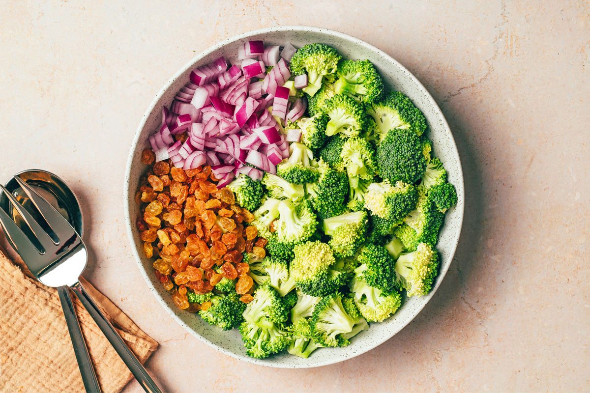 Ingredients combined into a large bowl for Broccoli Raisin Salad Recipe for Taste of Home
