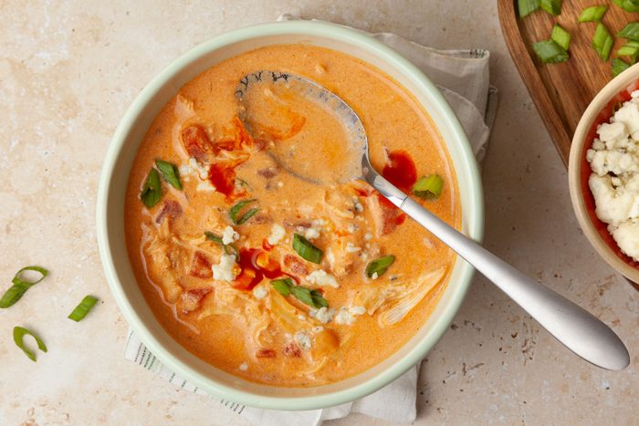 Single serving of Taste of Home Buffalo Chicken Chili garnished with blue cheese, green onions and a drizzle of extra buffalo sauce