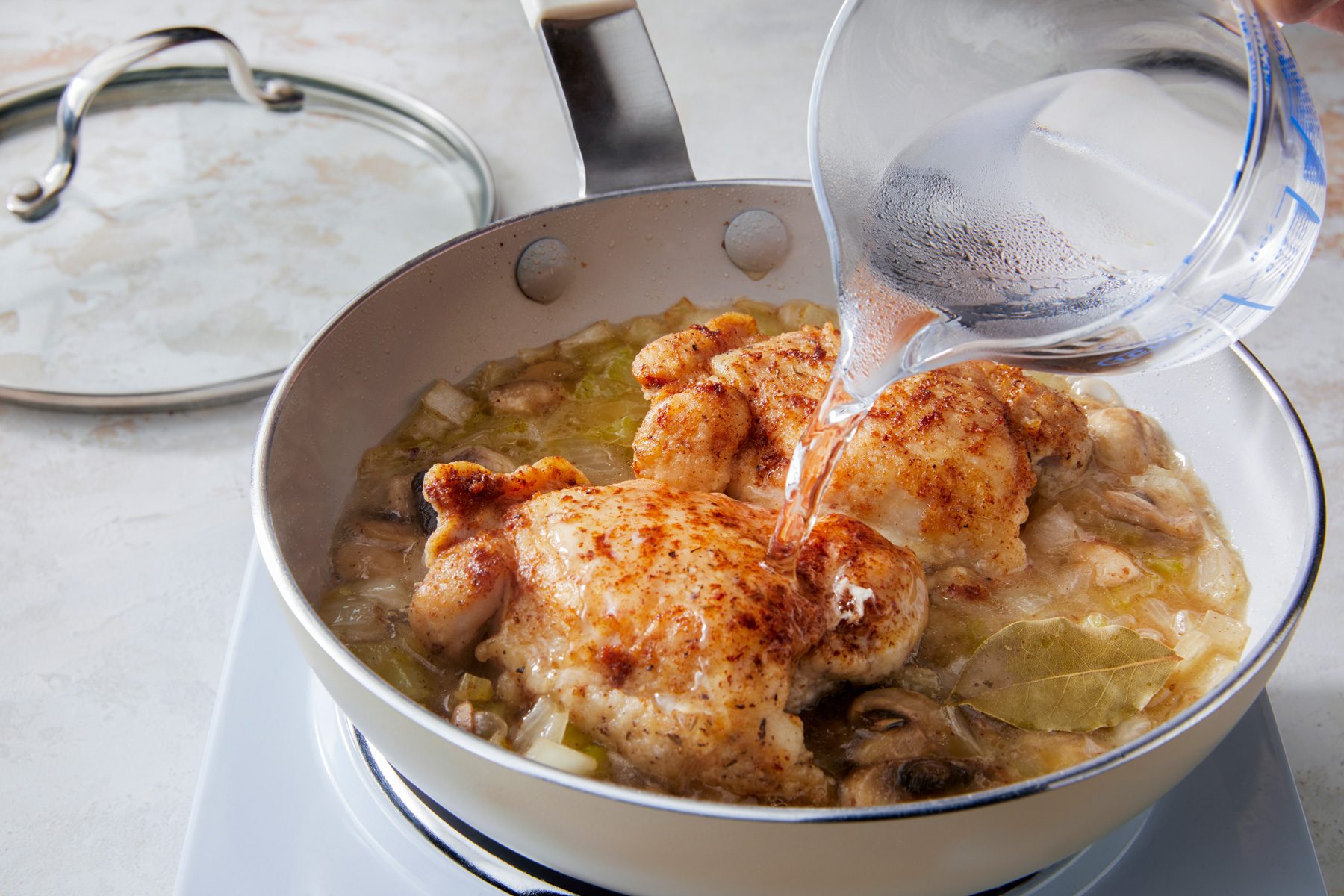 3/4th shot; white background; Added chicken back to skillet and added water simmer