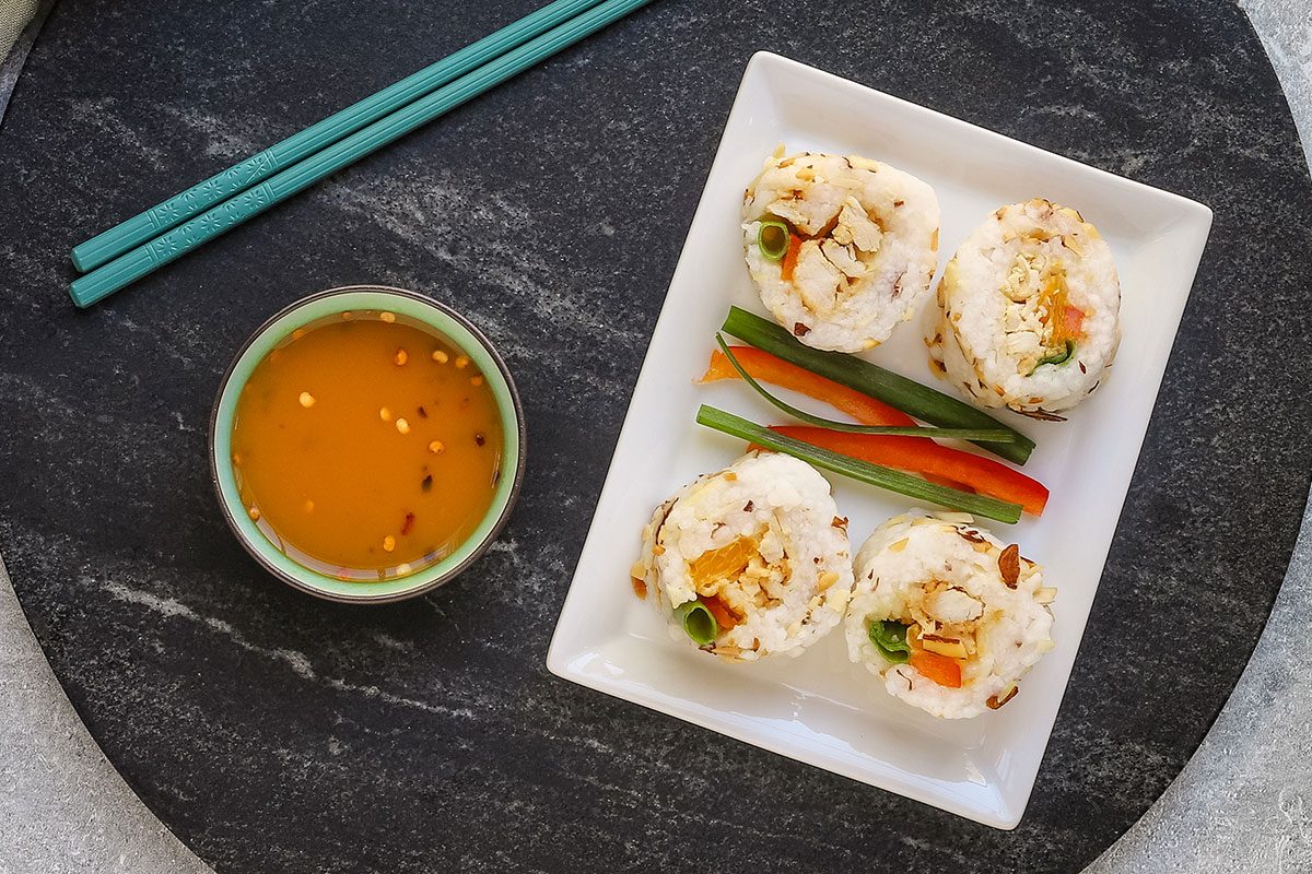Chicken tempura roll slices on a plate with dip on the side.