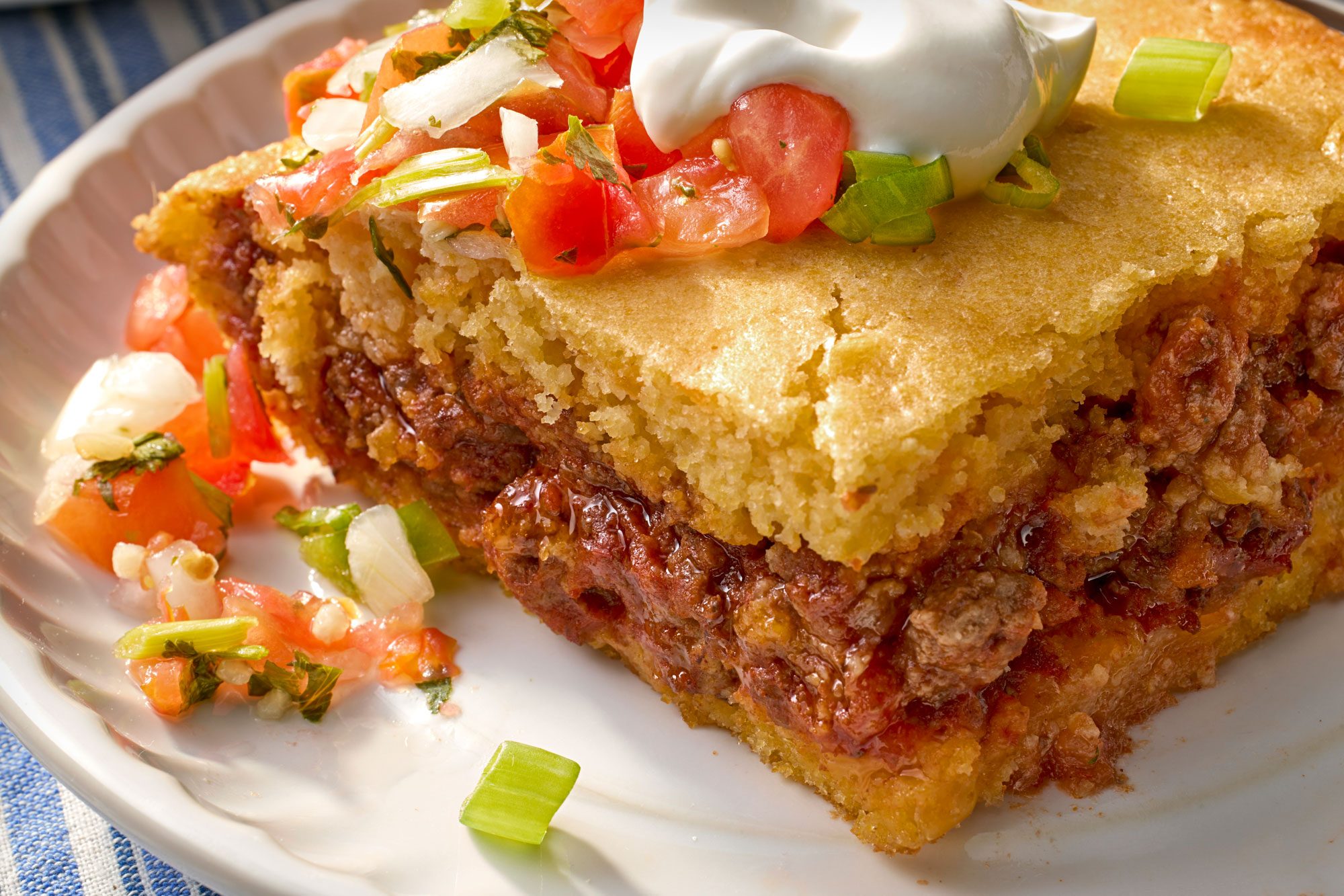 close shot of chili cornbread casserole served with sour cream and salsa