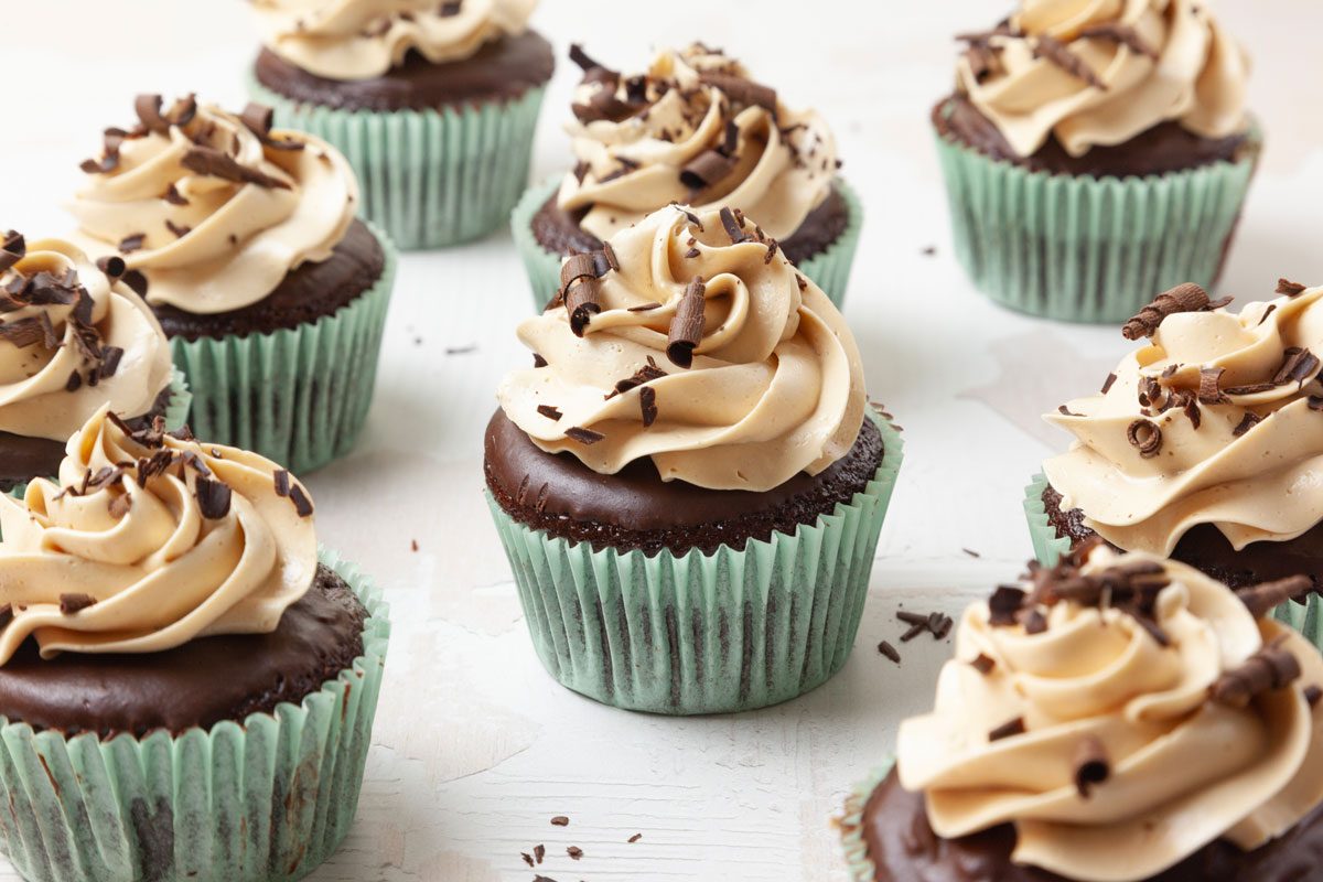 Taste of Home Chocolate Peanut Butter Cupcakes in light aqua liners, garnished with chocolate curls, on surface