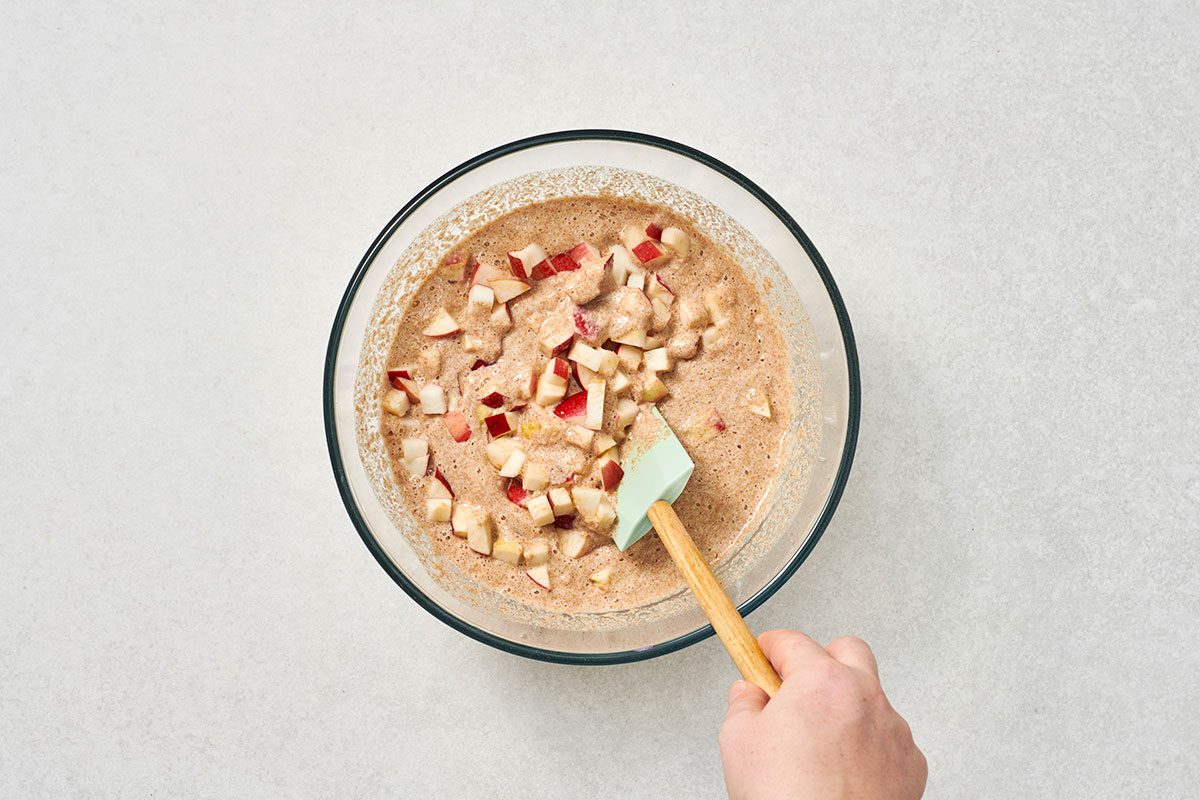 Chopped apples being stirred into the pancake batter