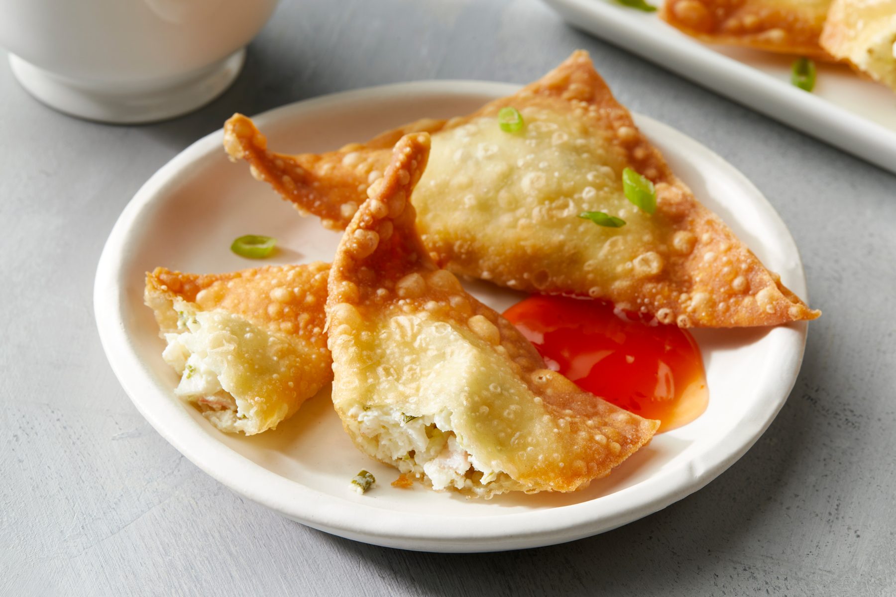 Crab Rangoon in two pieces open with sauce