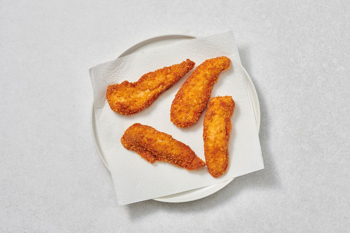 Cooked chicken tenders on paper towels on a plate