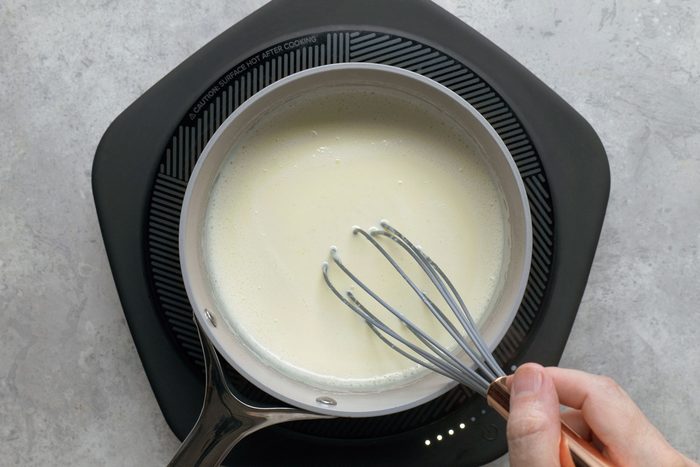 Stirring cream in a large saucepan using a whisker