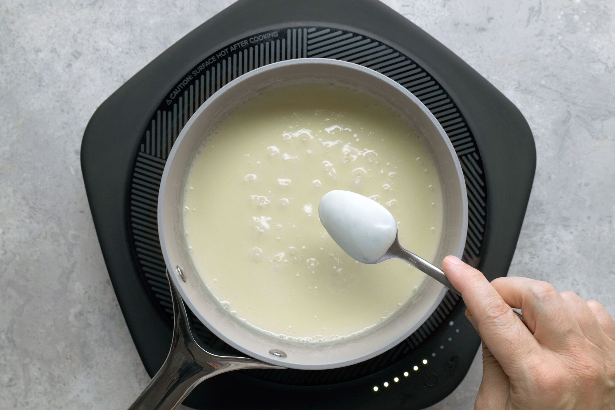 Checking the thickness of the cream over spoon backside in a saucepan