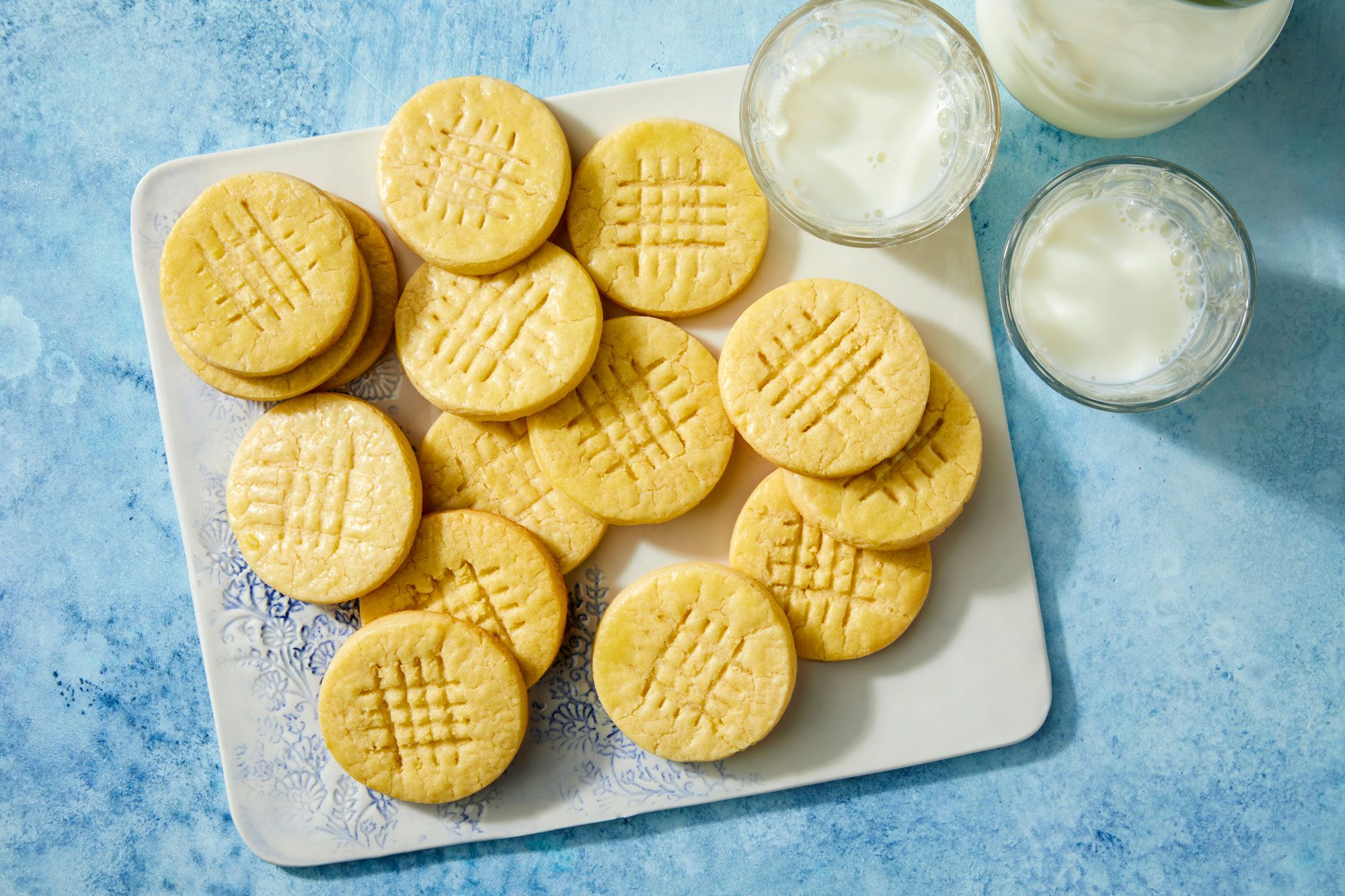 French Butter Cookies served in a plate with milk on the blue surface background