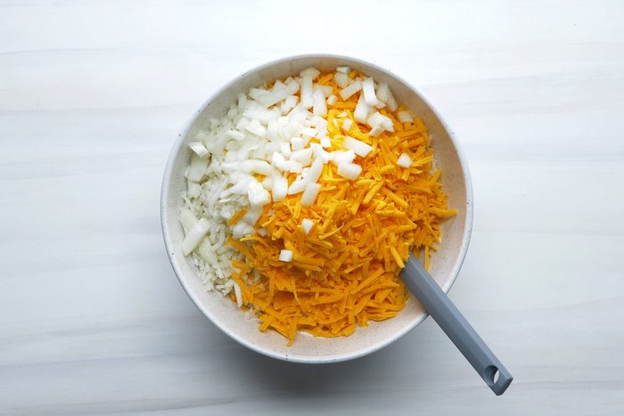 Potatoes, onion and cheese mixed in a large bowl.