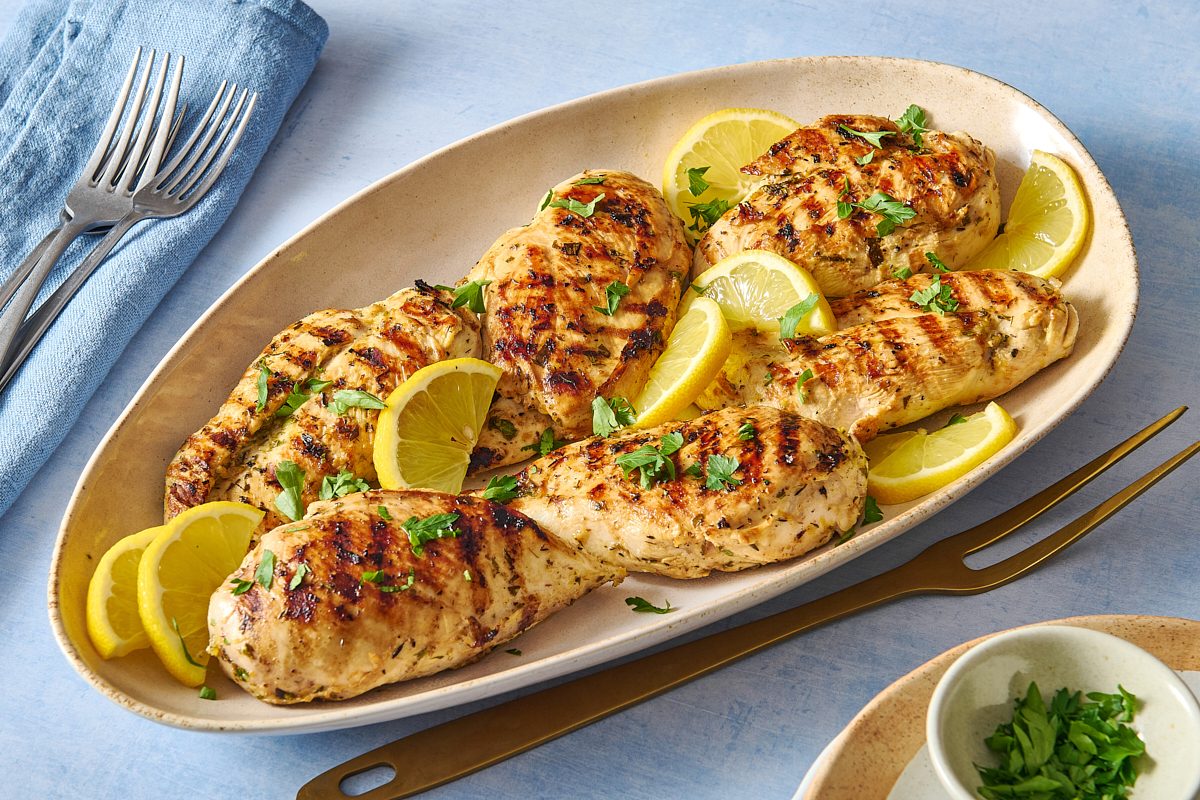 Angled shot of grilled lemon chicken breasts served on a platter