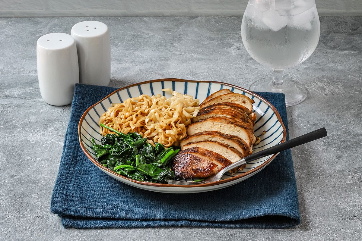 Grilled teriyaki chicken breasts on a plate with noodles and spinach, from a Taste of Home recipe.
