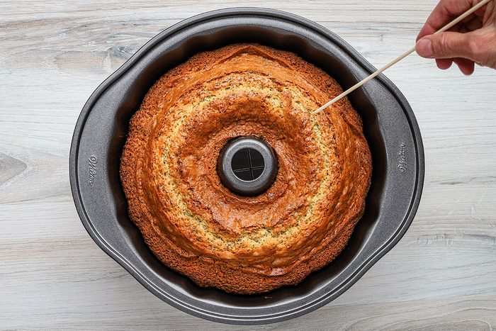 Testing the baked lemon poppy seed cake with a skewer.