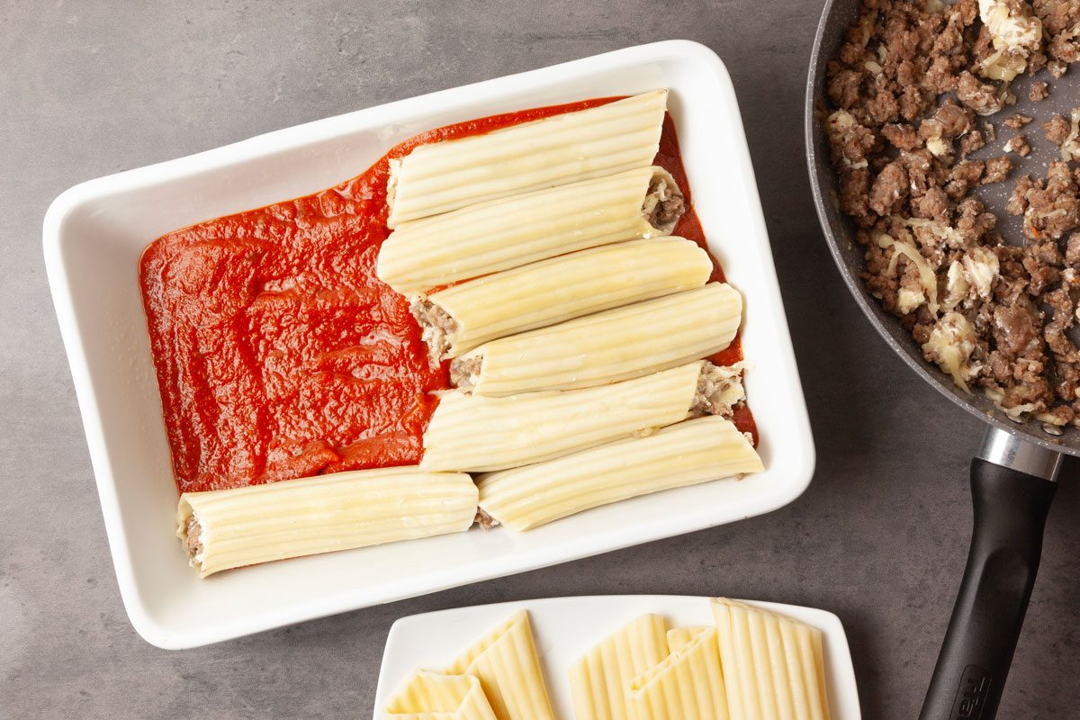 Step 5 of Taste of Home Meaty Manicotti is to stuff each shell with about 1/4 cup of the meat mixture, then arrange them over the sauce. Pour the remaining sauce over the top of the shells, then sprinkle them with grated Parmesan.