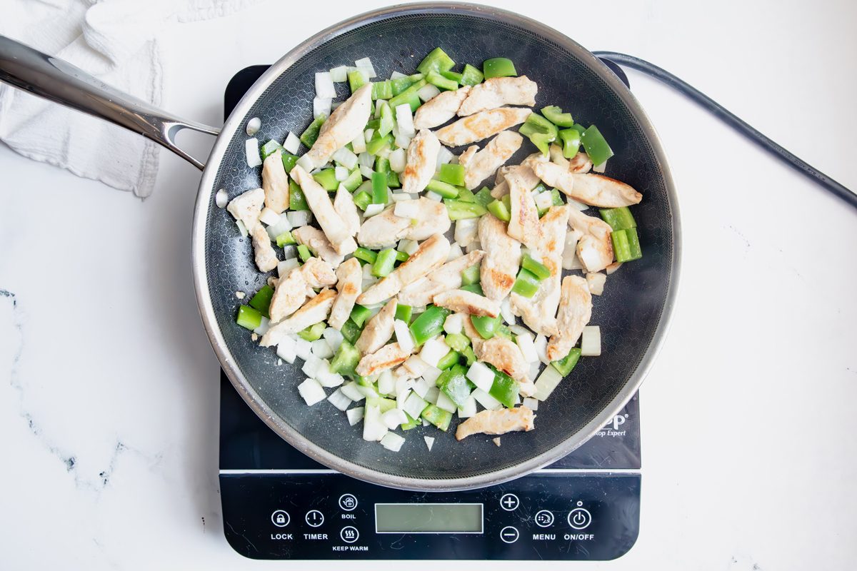 Overhead shot for Taste of Home Mexican Chicken and Rice with chicken, peppers, and onions in a hexclad cooking.