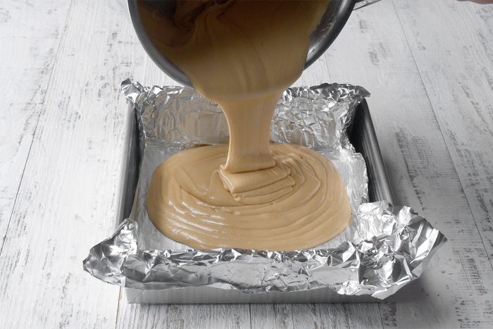 Angle view shot of pan with foil; immediately spread into prepared pan; white wooden background;