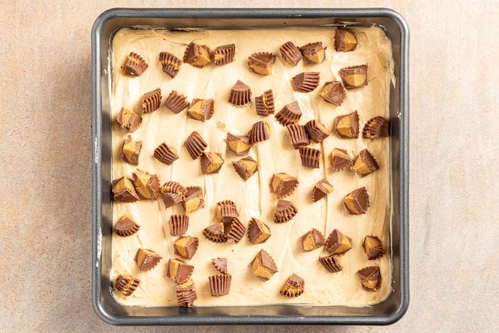 Taste of Home Peanut Butter Lasagna recipe photo of the first layer and chopped peanut butter cups added to the baking dish.