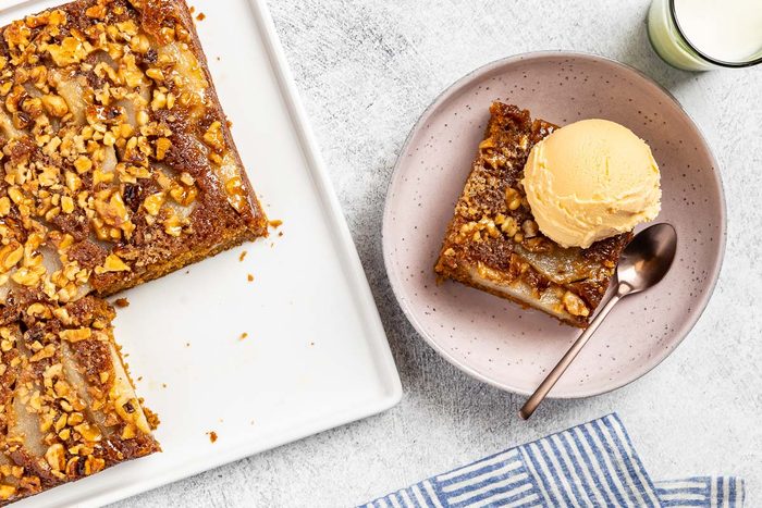 Taste of Home Pear Upside Down Cake recipe photo of the finished cake cute into a slice and topped with ice cream.
