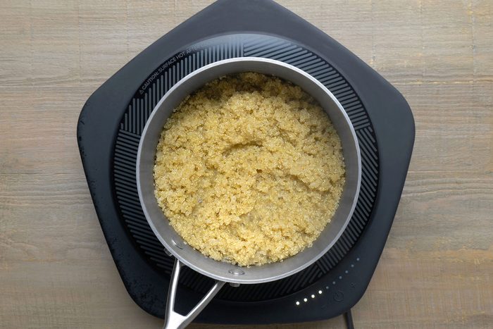 Quinoa simmering with water in a large saucepan.