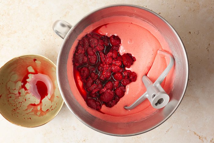 Step 1 of Taste of Home Raspberry Cake is to combine the cake mix, raspberry gelatin, eggs, canola oil and hot water in a large bowl. Beat on low speed for 30 seconds to combine the ingredients, then increase the speed to medium and beat for two minutes until the batter is smooth. Gently fold in the thawed raspberries along with their juices.