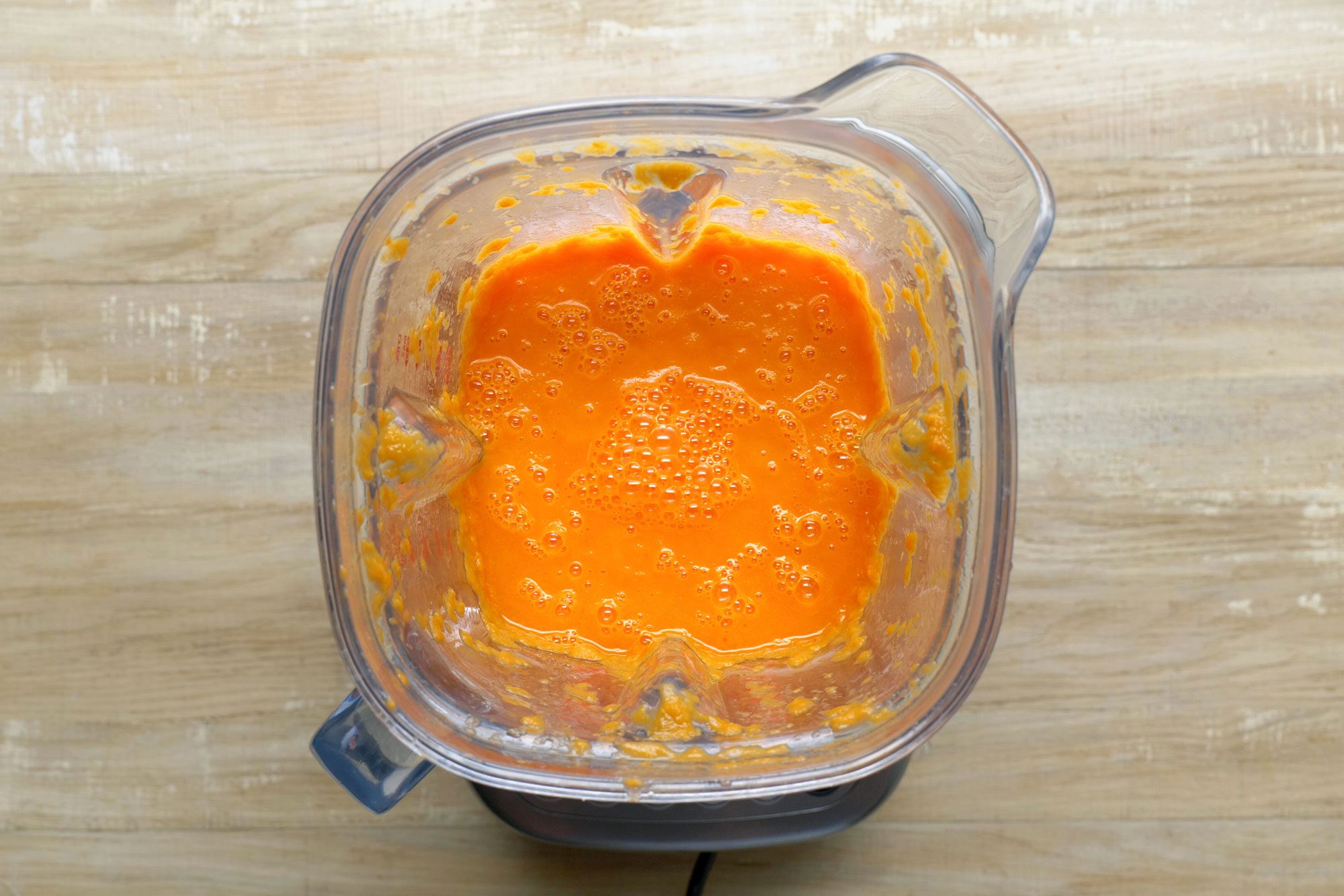 In a blender, process soup in batches until smooth; Wooden Background;