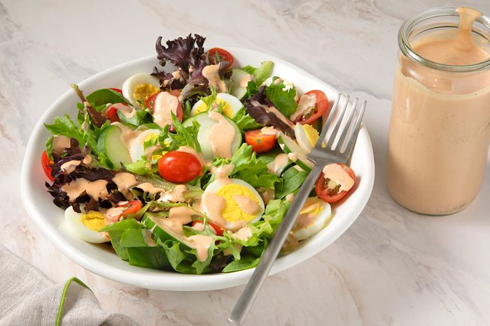 Russian Dressing next to a large bowl containing salad.