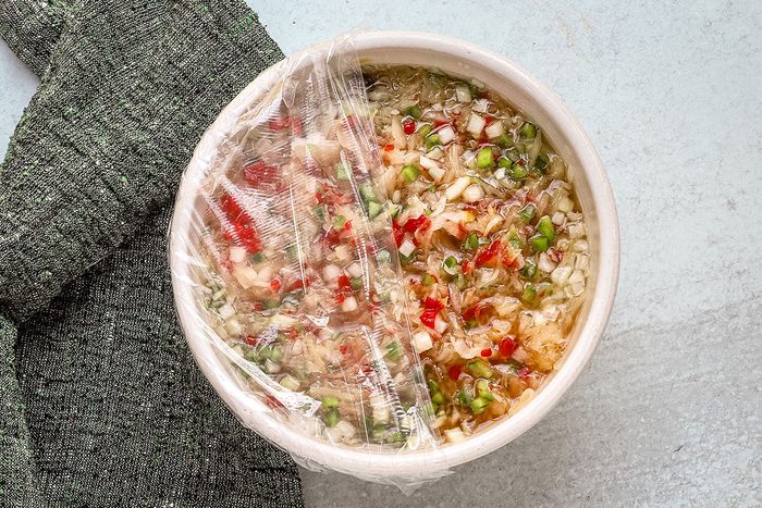 Saurkraut salad preparation, showing plastic wrap covering the bowl.