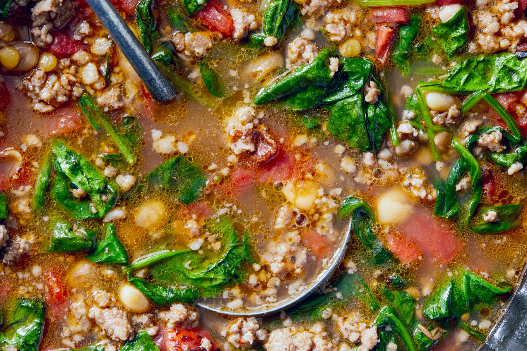 close view of Spinach and Sausage Lentil Soup, a serving spoon rests in the soup
