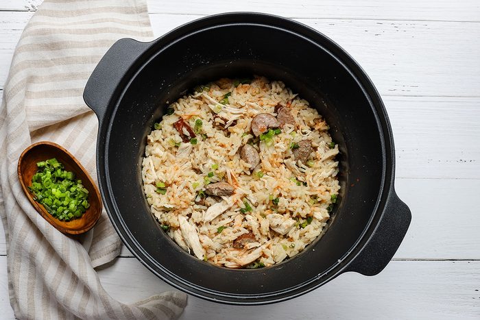 Chicken bog preparation in a slow cooker with green onions.
