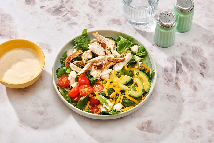 Chicken taco salad assembled on a serving plate with extra salad dressing on the side