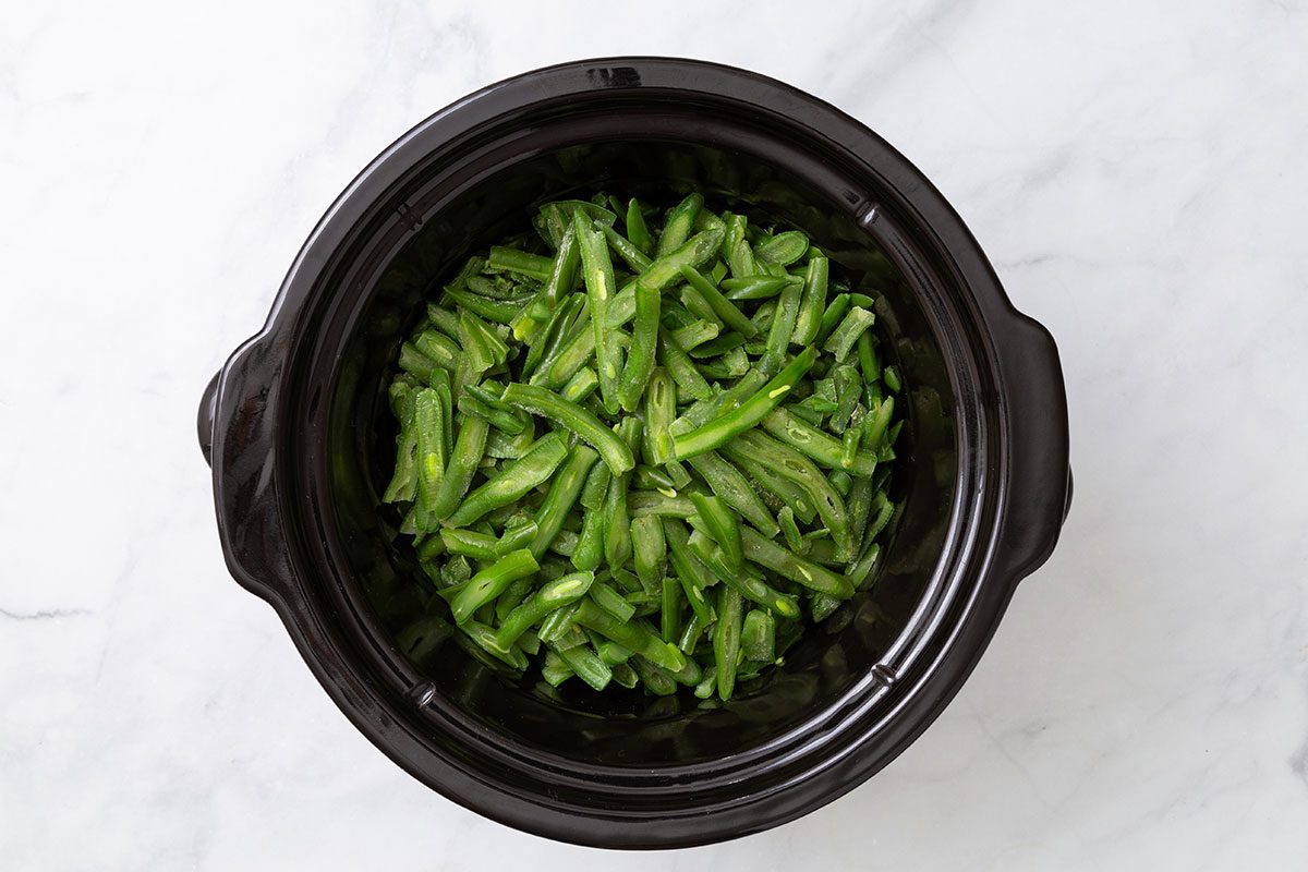French style green beans in a slow cooker for step one of Slow Cooker Green Beans recipe for Taste of Home