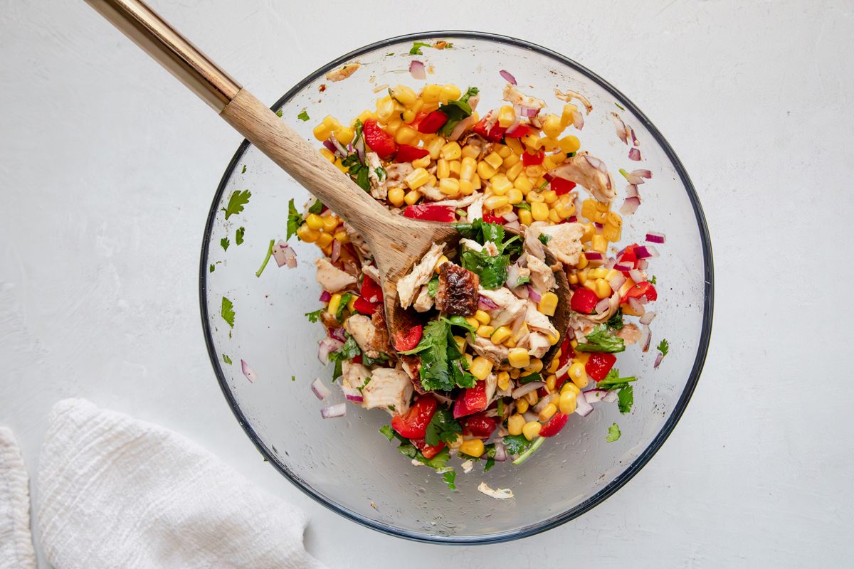 Overhead beauty shot for Taste of Home Southwest Chicken Salad, ingredients in a glass bowl mixed.