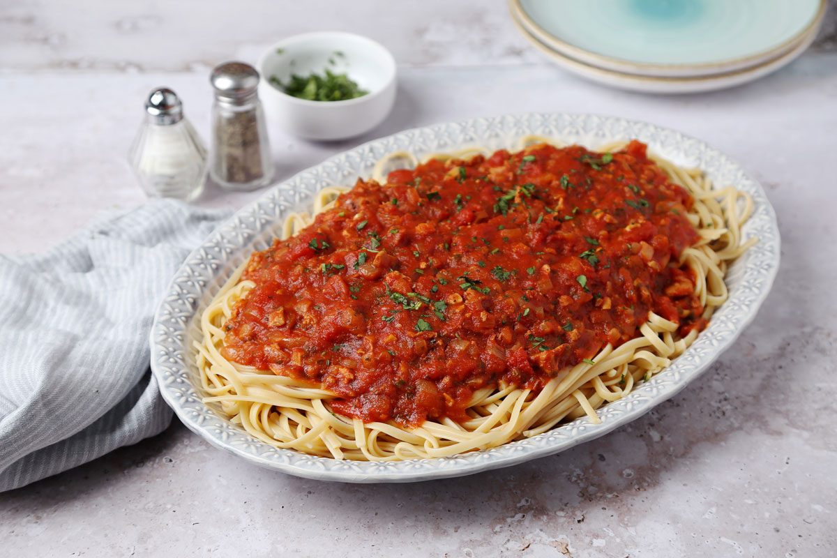 Close up of Taste of Home's Red Clam Sauce served on top of cooked linguine on a blue platter.