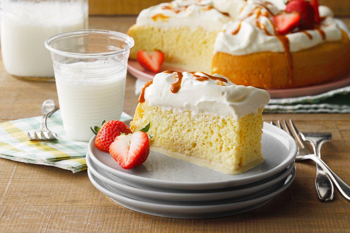 Tres Leches Cake slice served on a plate with a glass of milk to the side