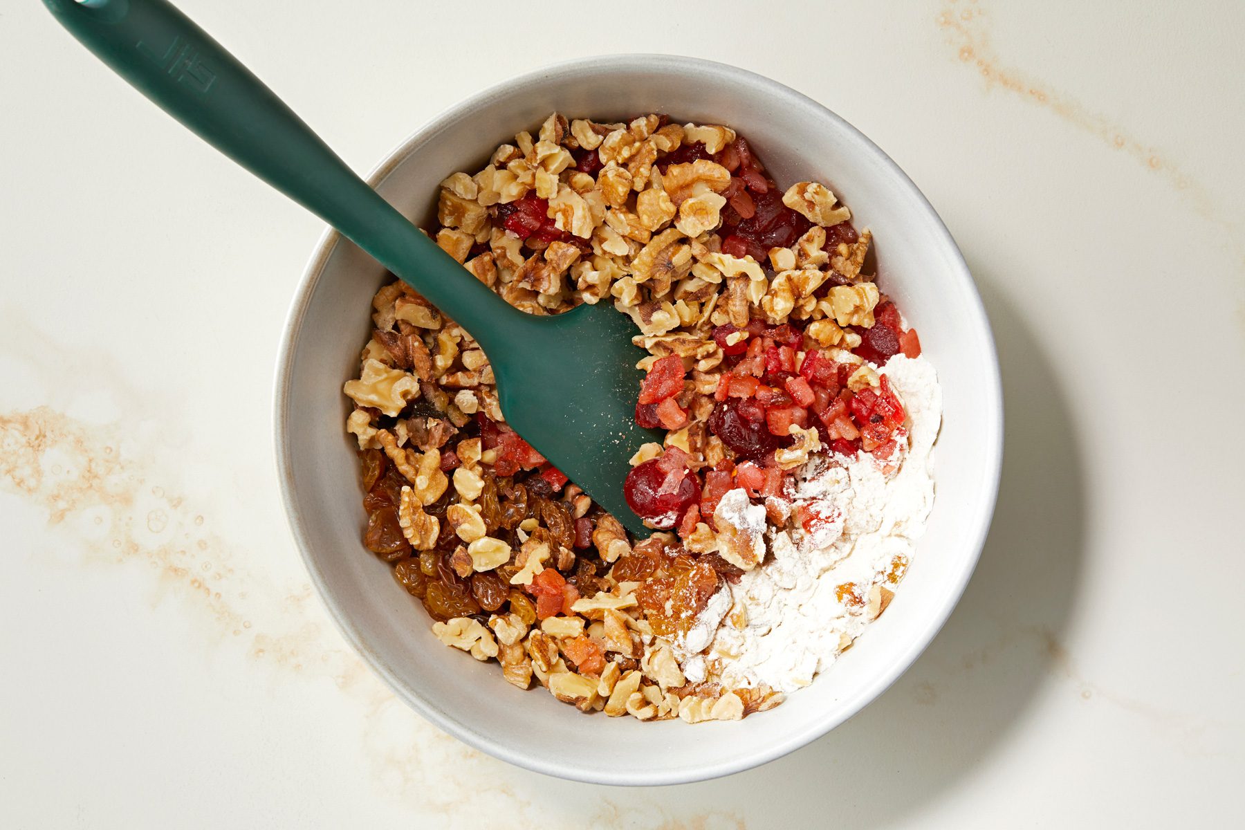 Tossing dried fruits in a bit of flour