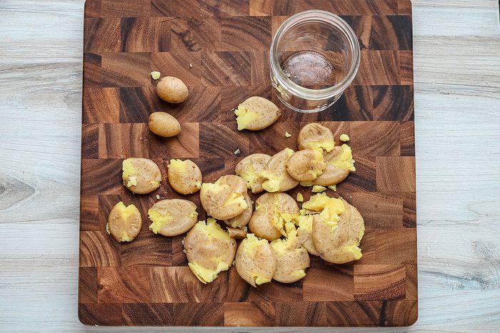 Air fryer smashed potato prep: flattening the potatoes with the bottom of a jar.
