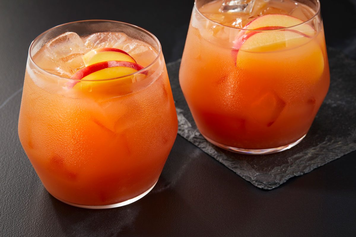 two glasses filled with a refreshing Bourbon Apple Cider Cocktail, The glasses are filled with ice and garnished with slices of apple