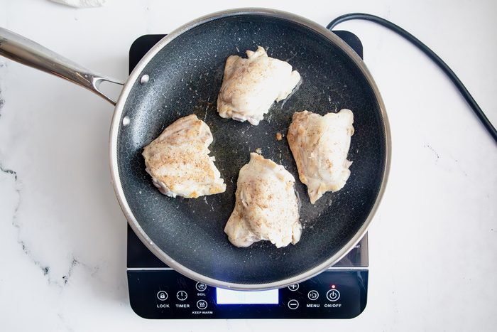 Overhead shot for Taste of Home Apple Chicken with chicken cooking on an induction cooktop.