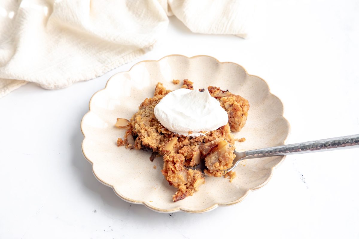 Beauty shot for Taste of Home Apple Streusel with a serving on a plate topped with whipped cream and spoon.
