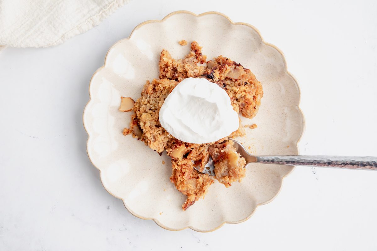 Top down beauty shot for Taste of Home Apple Streusel with a serving on a plate topped with whipped cream and spoon.