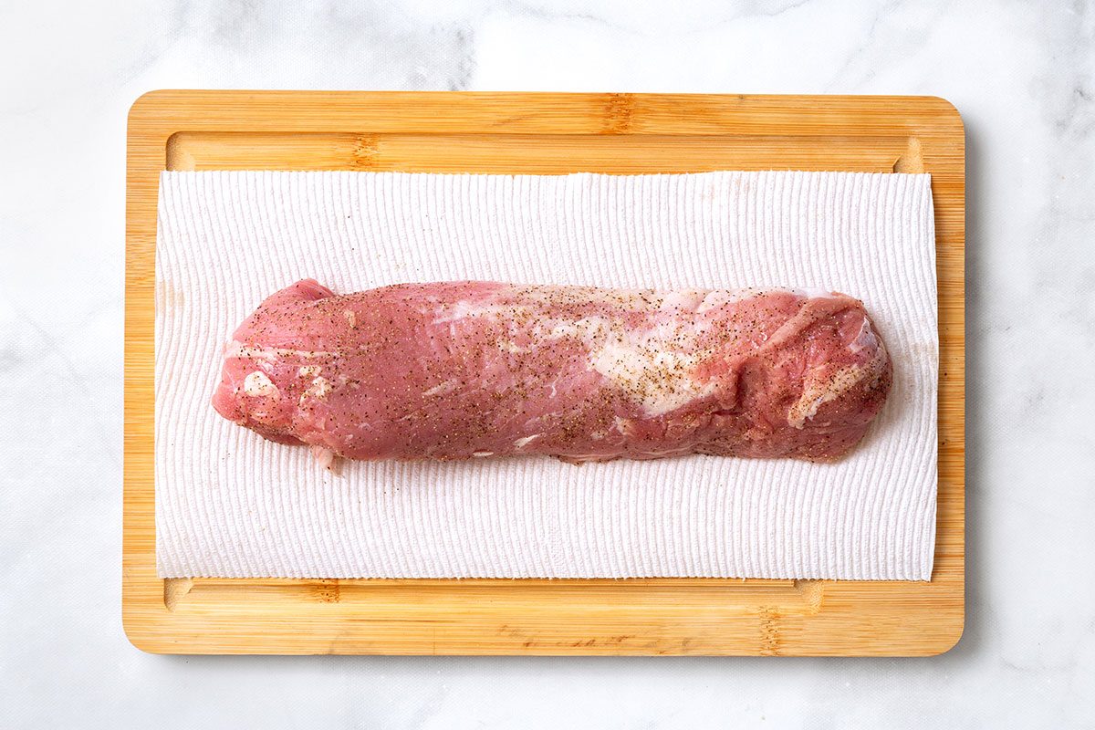 Seasoned pork tenderloin on wooden cutting board for step one of Balsamic Pork Tenderloin recipe for Taste of Home