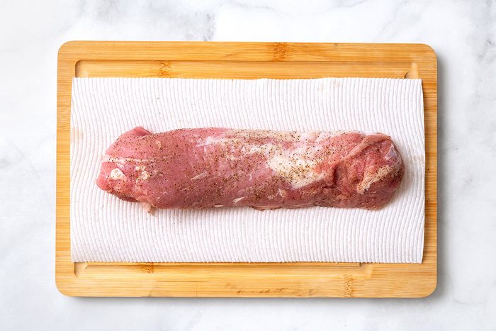 Seasoned pork tenderloin on wooden cutting board for step one of Balsamic Pork Tenderloin recipe for Taste of Home